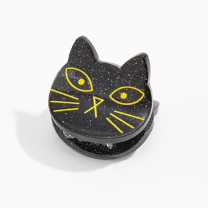 Détail d'une pince à cheveux noire pailletée en forme de chat avec détails jaunes