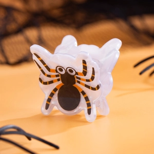 Détail d'une pince à cheveux à motif d'araignée sur un fond orange festif