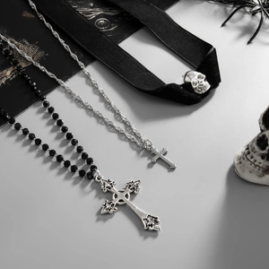 Detailed view of punk cross beaded necklace and skull choker on gothic backdrop