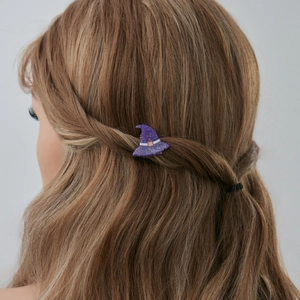 Détail de la pince à cheveux chapeau de sorcière violet pailleté sur cheveux blonds bouclés