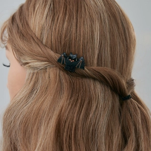 Détail d'une pince à cheveux chauve-souris noire pailletée sur des cheveux châtains ondulés