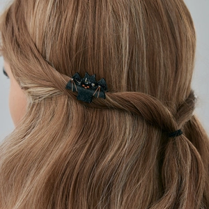 Gros plan sur une pince à cheveux chauve-souris pailletée pour Halloween sur cheveux bruns