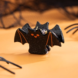 Détail d'une pince à cheveux chauve-souris pailletée avec des accents orange vif