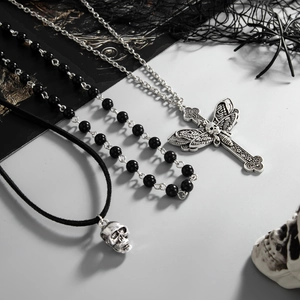 Macro shot of gothic necklaces featuring silver cross, moth skull charms and beaded chains