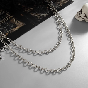 Detail of silver multi-layer metal waist chain with cross pendant on gothic background