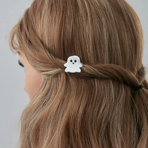 Détail macro d'une pince à cheveux fantôme blanc portée sur des cheveux ondulés