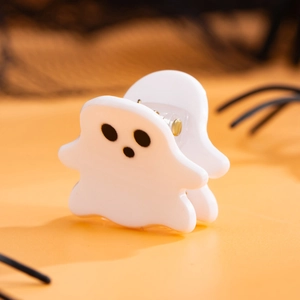 Gros plan d'une pince à cheveux fantôme blanc en acétate sur fond festif d'Halloween
