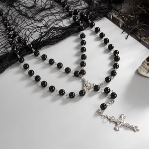 Detail view of black beaded Gothic rosary necklace with silver cross on spider net background