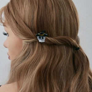Détail de la pince à cheveux crâne avec chapeau de sorcier sur une coiffure tressée