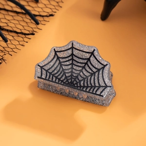 Macro d'une pince à cheveux d'Halloween avec motif toile d'araignée sur fond pailleté argent