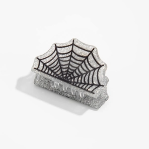 Détail de la pince à cheveux argentée pailletée avec motif de toile d'araignée noire