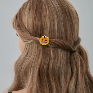 Détail d'une pince à cheveux citrouille orange avec visage d'Halloween sur cheveux