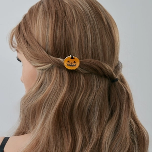 Détail d'une pince à cheveux citrouille d'Halloween avec un design orange Jack-o'-lantern