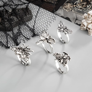 Macro shot of four vintage silver moth rings with gothic relief details on a gray surface