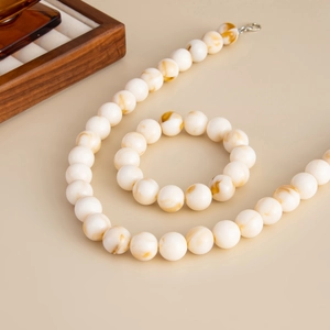 Nahaufnahme der böhmischen Acrylperlenkette und des Armband-Sets mit Bernsteintextur