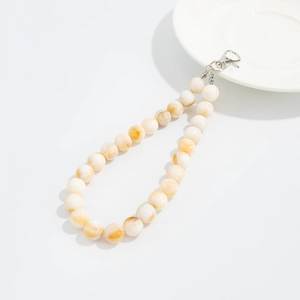 Close-up of marble textured beige acrylic beads and silver metal clasp on a bag charm