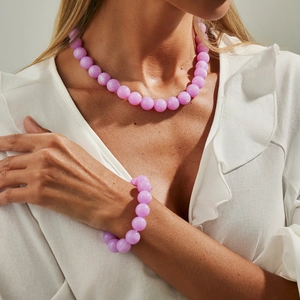 Nahaufnahme der hellvioletten Acryl-Perlenkette und Armband-Set auf weißem Kleid