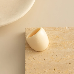 Close-up of a cream resin chunky dome ring on a textured stone display stand
