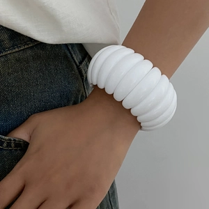 Detail of wide white resin cuff bracelet with wavy texture worn by a model