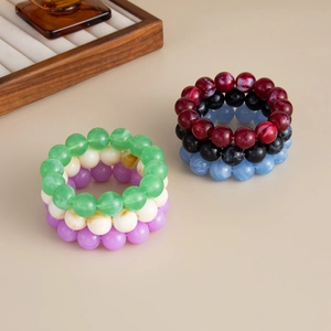Nahaufnahme von geschichteten Acryl-Perlenarmbändern im Boho-Stil mit Marmoreffekt