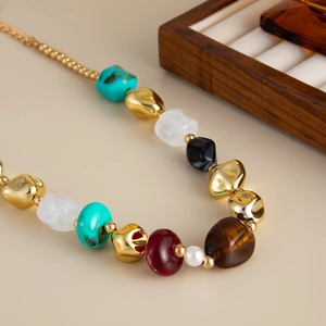 Dettaglio di collana bohémien in resina colorata con CCB dorate irregolari e perle