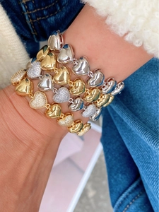 Détail de bracelets empilés en forme de cœur en or 18 carats et argent avec zircons