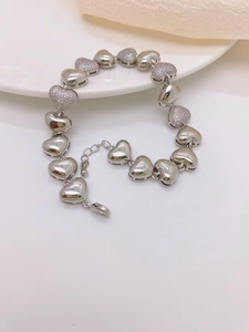 Détail du bracelet cœur argenté avec surfaces polies et pavage de zircons scintillants