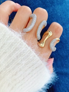Detail of 18K gold plated rings with zircon inlay and irregular organic wave patterns