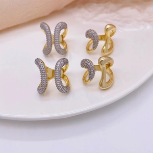 Detailed view of four 18K gold plated zircon rings on a white ceramic plate