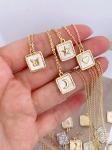 Detail of four gold-plated pendants with white mother-of-pearl and 3D celestial motifs