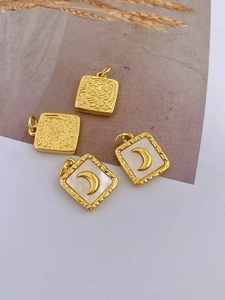 Detail of square gold plated DIY charms with embossed textures and white moon inlay