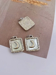 Detail of vintage gold plated shell moon pendants with hammered metal texture details