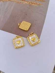 Detailed macro view of square gold pendants with heart motifs and lava texture finish