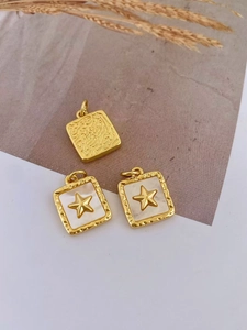 Detailed view of square gold plated pendants with shell inlay and star relief carving