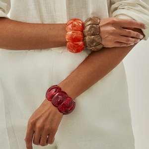 Detail view of wide resin bracelets with marble texture in amber, orange and crimson hues