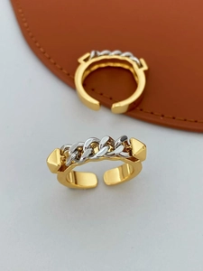 Detailansicht eines vergoldeten Rings mit silbernem Kettenglied und Punk-Kegelnieten