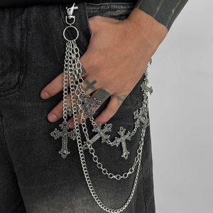 Détail de la chaîne de taille punk argentée avec pendentifs croix sur un jean noir