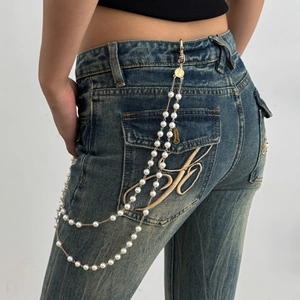 Cross pendant pants chain with white pearls and gold metal links on denim jeans