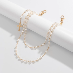 Detail of double-layer pearl chain with gold cross pendant and lobster clasp fasteners