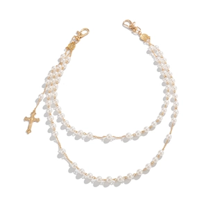 Detail of multilayer pearl waist chain with golden cross pendant and lobster clasps