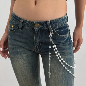 Detail view of silver cross pendant and faux pearls on a stylish layered waist chain