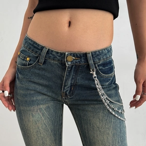 Detailed view of punk star chain belt on vintage washed blue denim jeans for women