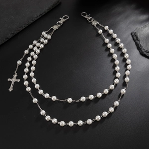 Detailed macro view of double-layered pearl pants chain with silver cross pendant decor