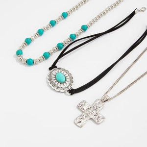 Dettaglio della collana con perline turchesi, ciondolo in pelle e croce in argento stile boho