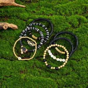 Detail of Game Day bracelet set with black clay beads and football charms on green moss