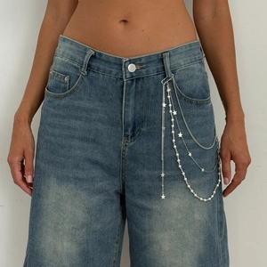 Detail view of multi-layer waist chain with star pendants and faux pearls on denim