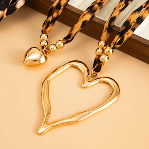 Macro shot of oversized gold hollow heart pendant with leopard print silk scarf ribbon