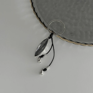 Detail of minimalist bag charm featuring dark marquise crystal and silver waterdrop pendants