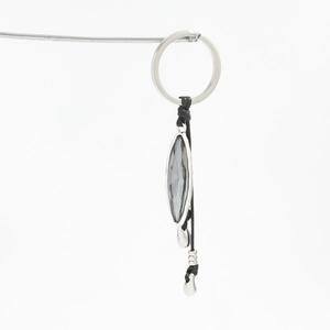 Detail of silver keychain with marquise-cut grey gemstone and metallic beads on white background