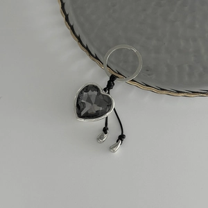 Detail of dark grey heart-shaped crystal keychain with silver metallic frame and black cord